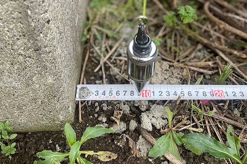 擁壁の下側を測定、擁壁からの距離が9センチの部分を指している振り子部分
