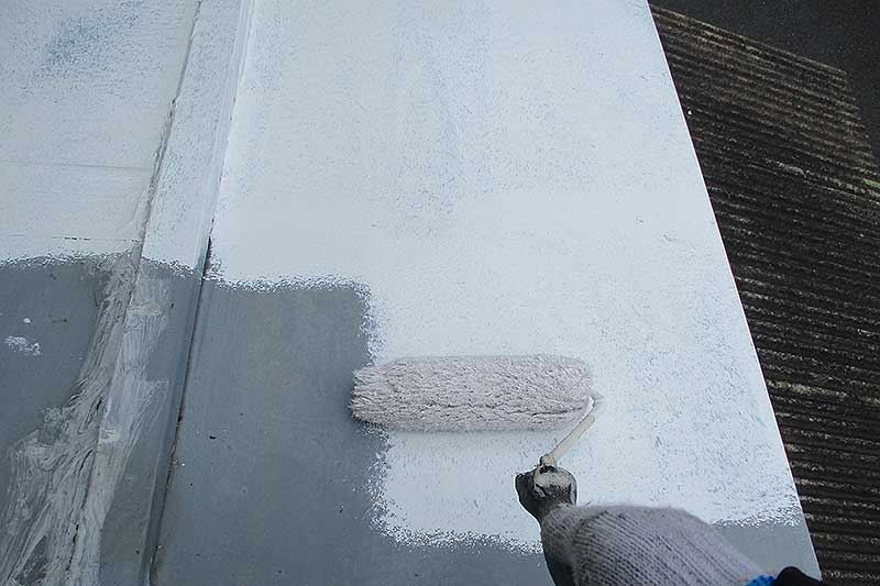 ローラーを使用して下屋根の下塗り作業