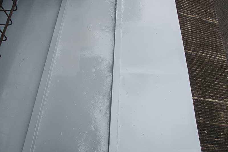 ローラーを使用した下屋根の上塗り作業