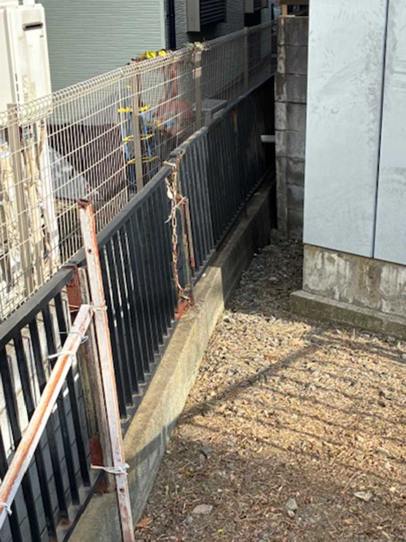 既存の傾いた擁壁と歪んだフェンス