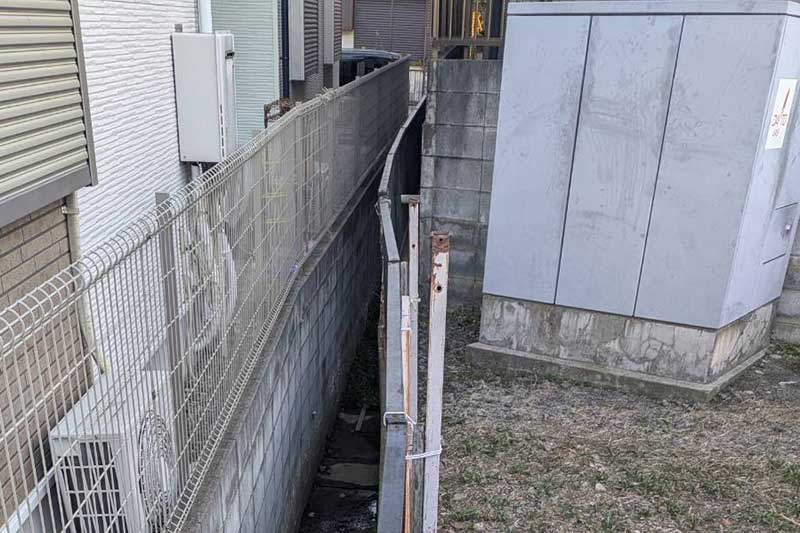 既存の傾いた擁壁と歪んだフェンス